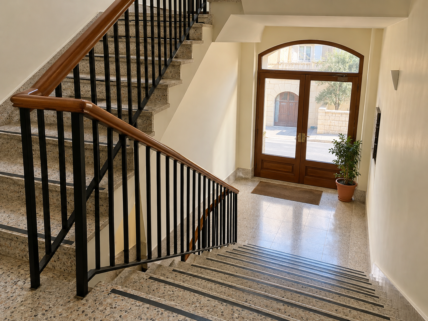Clean Maltese condominium entrance with terrazzo stairs and wooden handrails